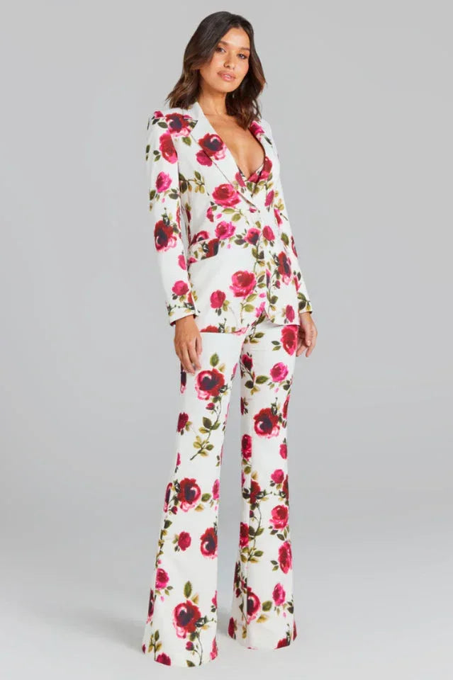 Woman in a white floral print suit, standing.