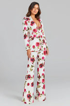 Woman in a white floral print suit, standing.