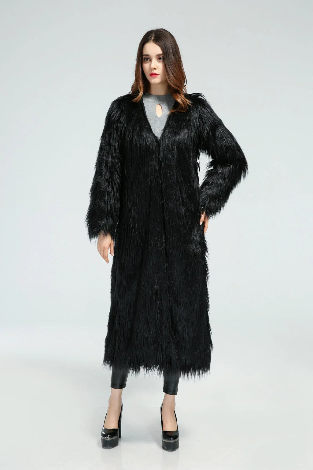 Woman with hands on hips wearing a black longline faux fur coat.