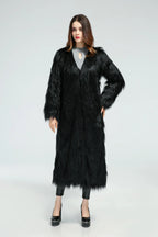 Woman with hands on hips wearing a black longline faux fur coat.
