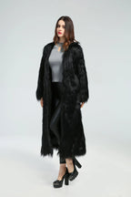 Full-length view of a woman in a black longline faux fur coat.