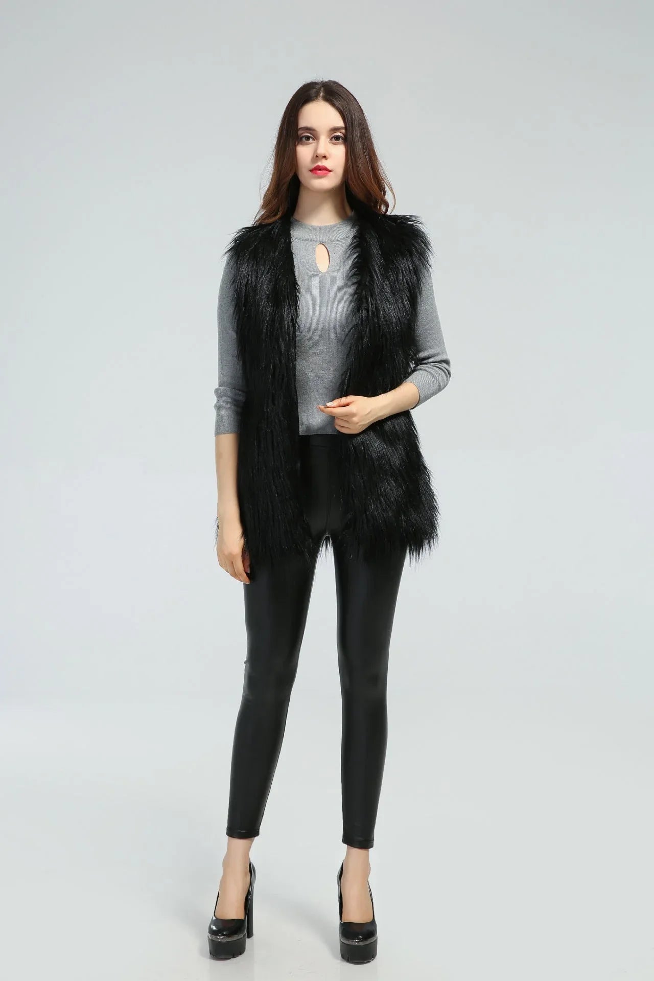 Woman wearing a black faux fur vest over a grey long-sleeved shirt and black pants, front view Main image