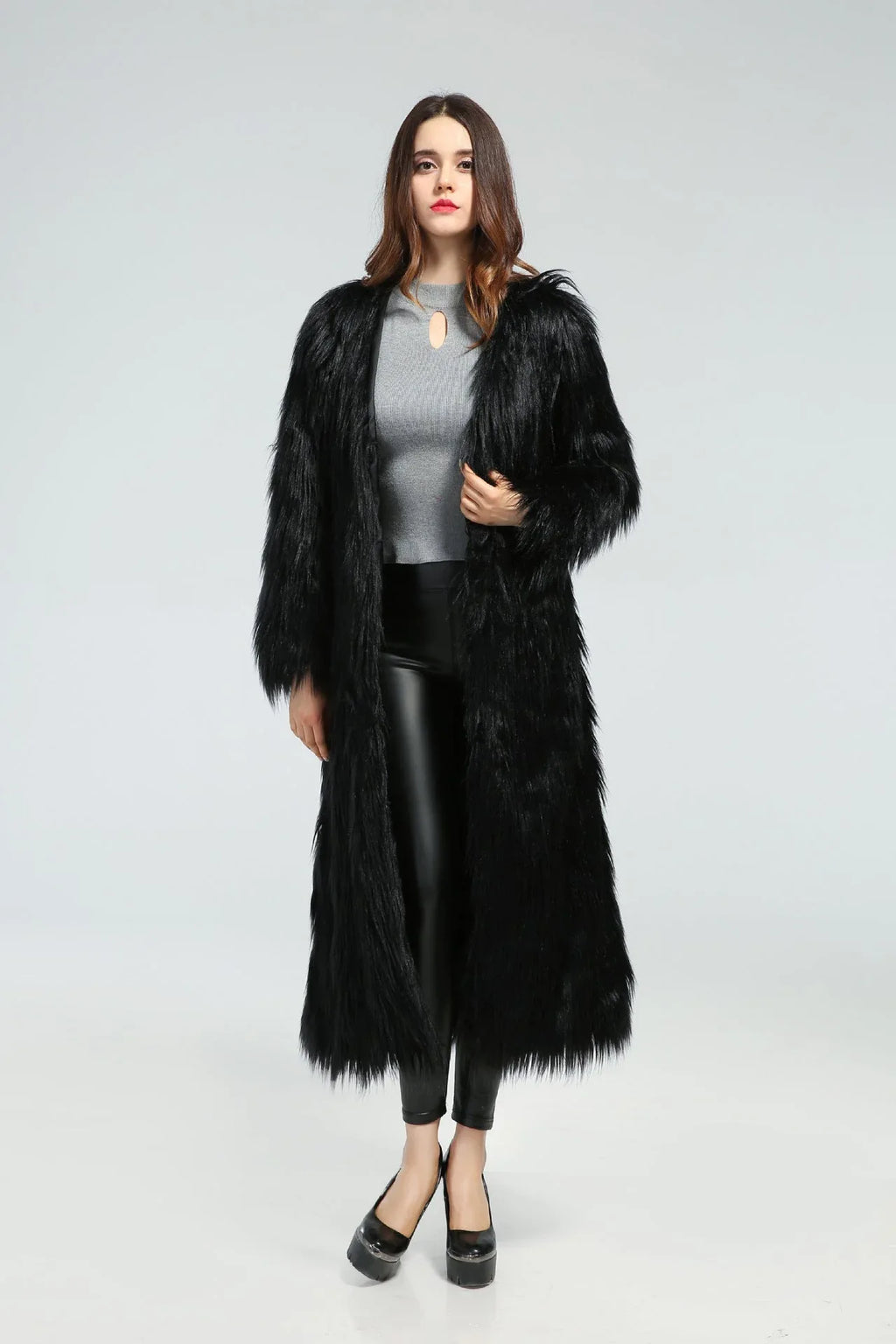 Woman wearing a black longline faux fur coat over a grey top and black leggings.