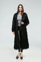 Woman wearing a black longline faux fur coat over a grey top and black leggings.