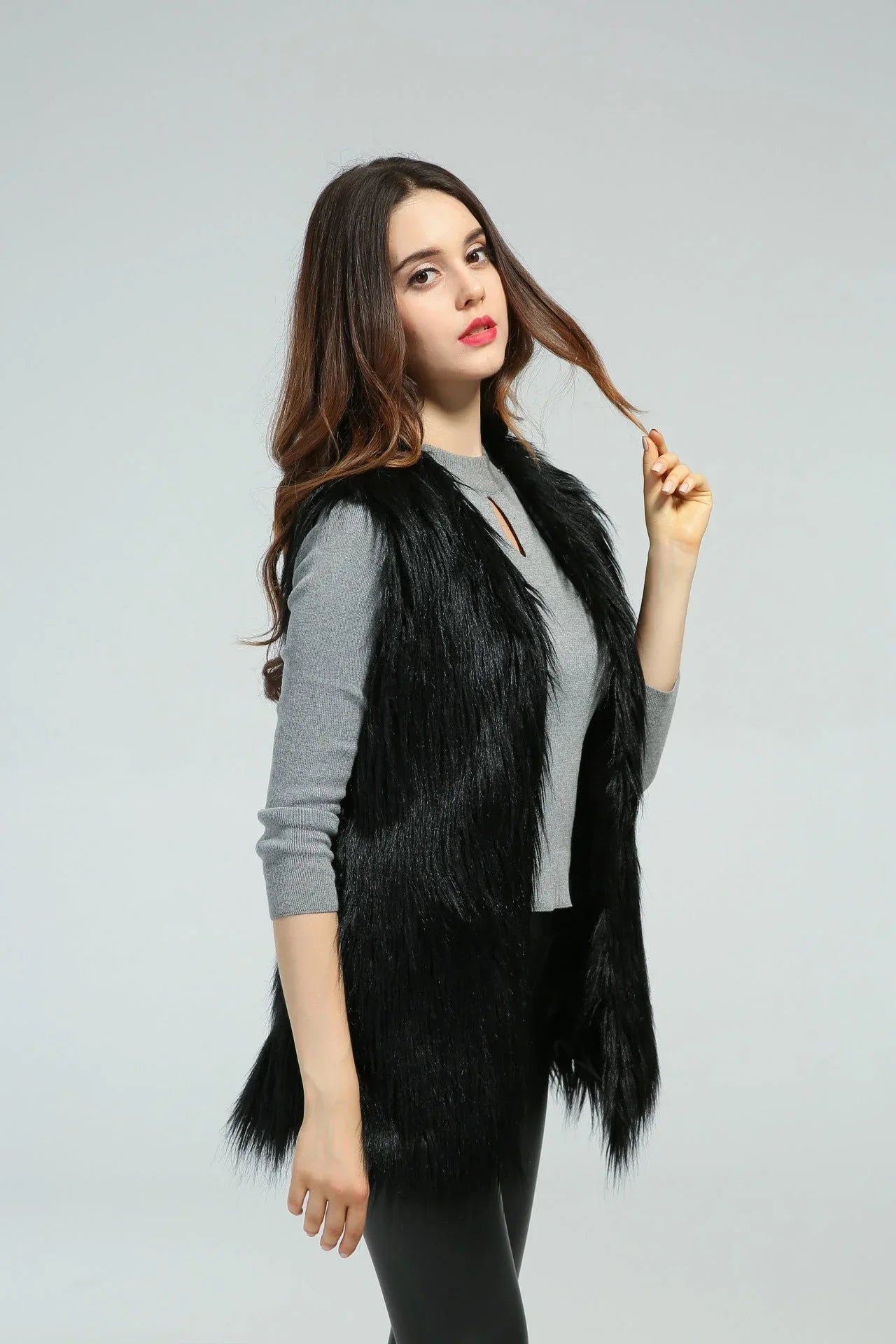 Woman in a black faux fur vest and grey shirt, side view