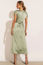 Back view of a woman in a sage green satin wrap midi dress with a tie detail