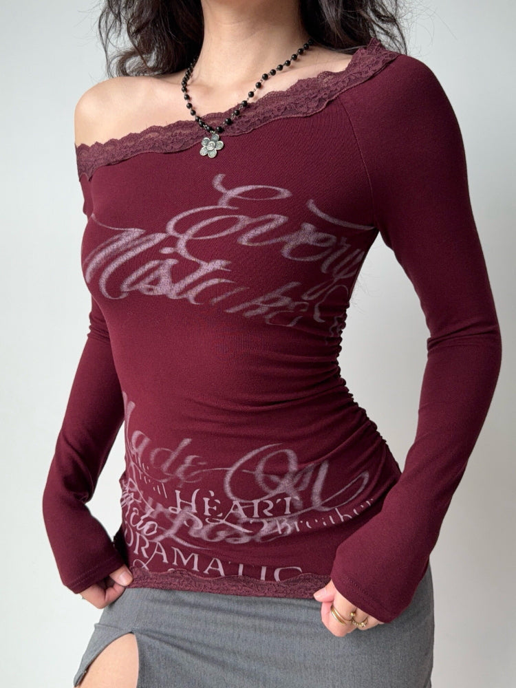 Close-up of a burgundy ribbed knit top featuring an off-the-shoulder design and white graphic text