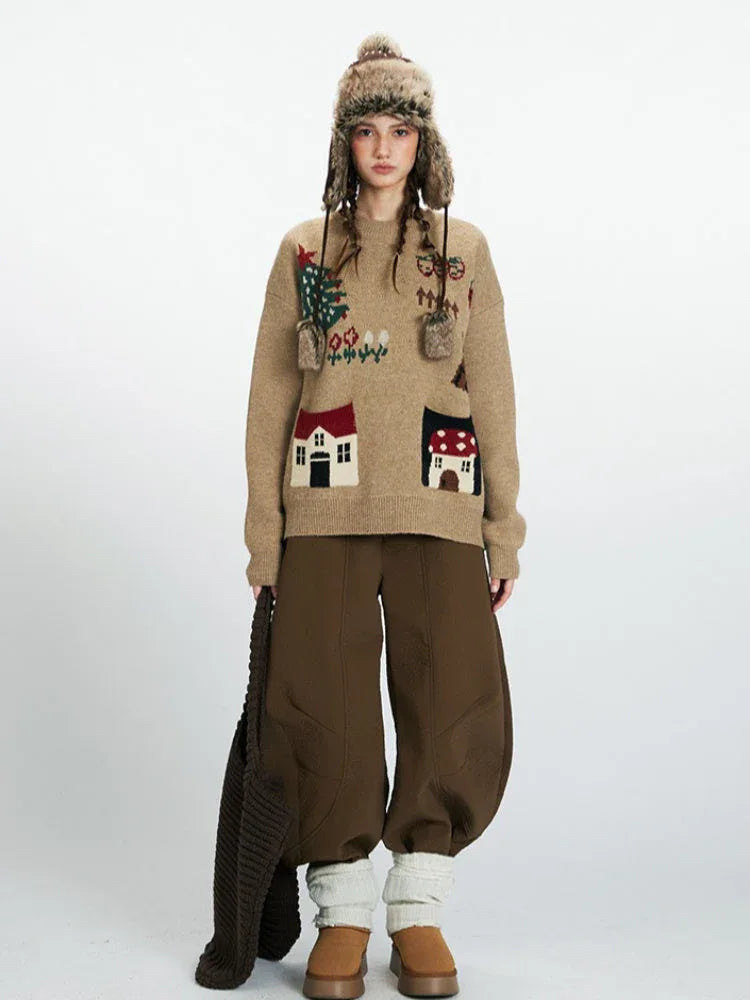Woman wearing a tan knit sweater with house appliqués and a winter hat