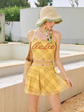 Yellow plaid halter neck bikini top and matching skirted bottom with embroidered graphic, worn by a model with a straw hat.