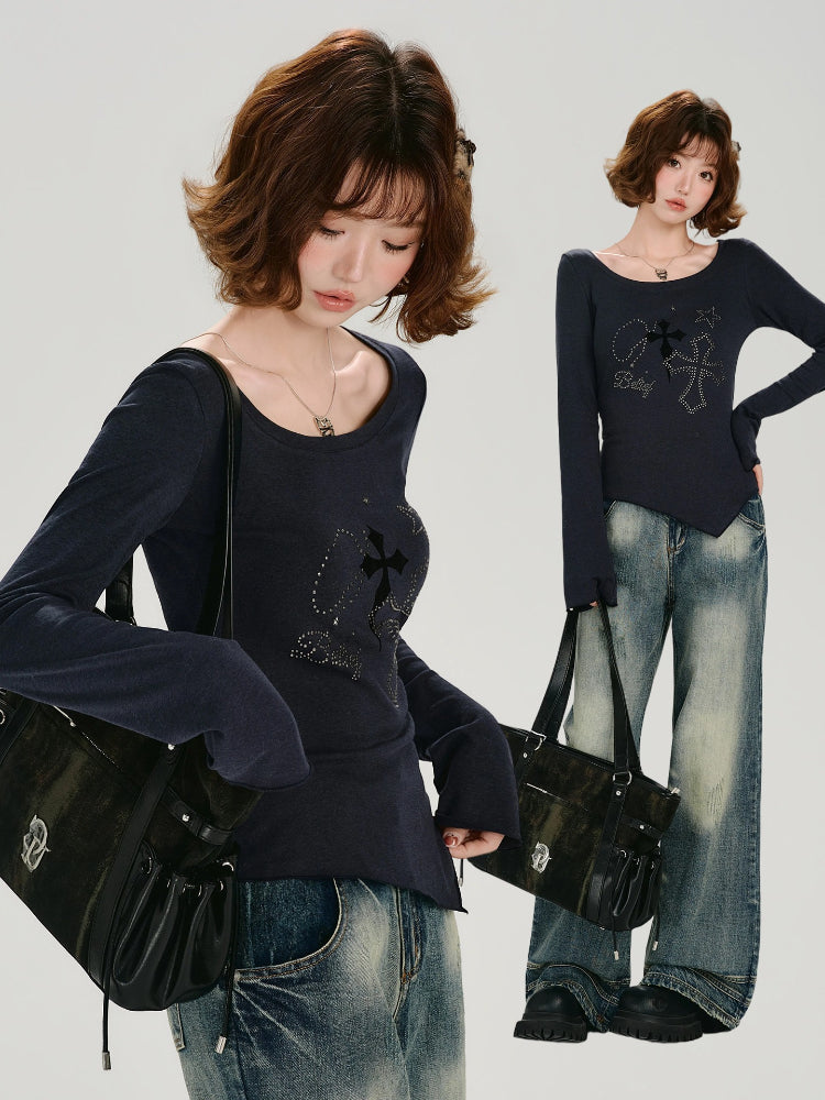 Woman wearing a dark blue long-sleeve graphic t-shirt and wide-leg jeans, holding a black handbag