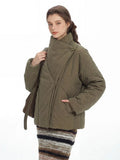 Close-up of a woman wearing an olive green quilted jacket with an asymmetrical collar and gold clasp detail.