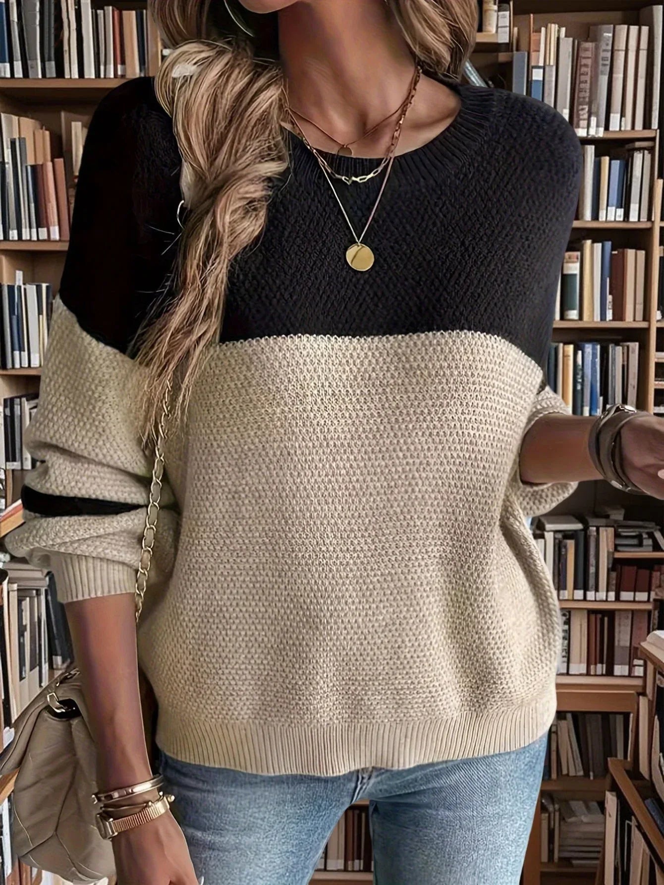 Three-quarter view of a woman in a casual knit sweater and jeans, showcasing the sweater's texture and color blocking.