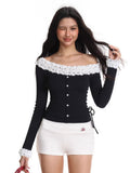 Close-up of a woman wearing a black long-sleeved top with white ruffled trim along the off-the-shoulder neckline.
