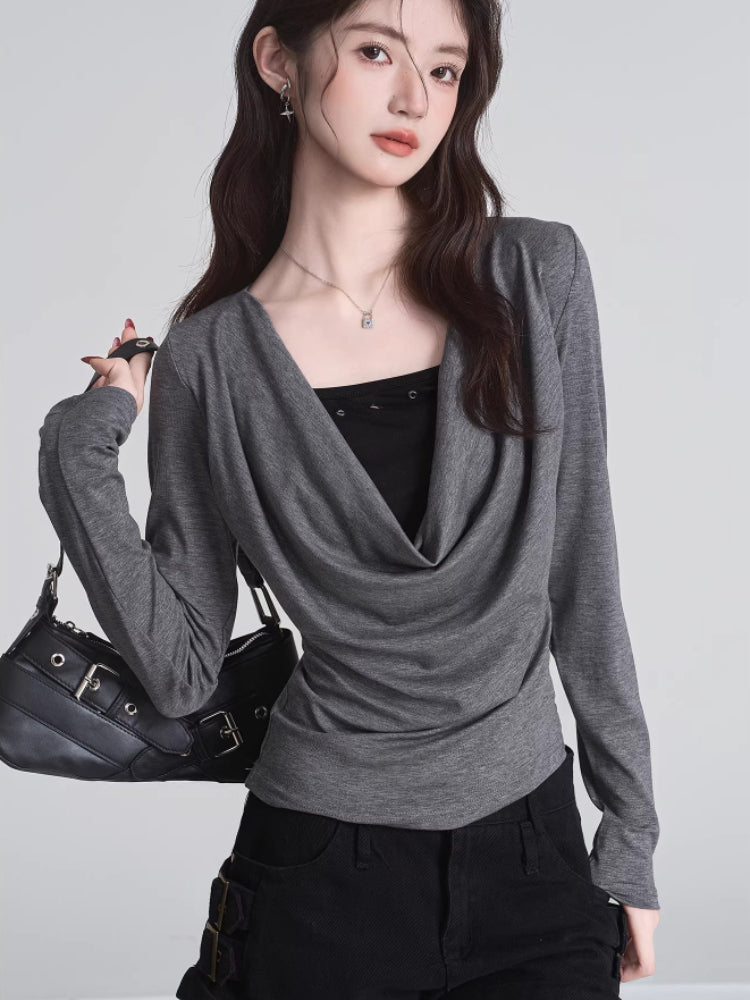 Woman holding black handbag with grey draped cowl neck long sleeve top