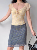Model wearing a yellow floral print mesh top and a patterned skirt