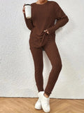 Woman holding a white cup while wearing a brown ribbed knit loungewear set with a crew neck top and slim-fit pants.