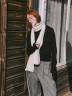 Woman wearing a cream-colored textured knit scarf and a black sweater.