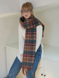 Woman wearing a plaid scarf with fringed edges.
