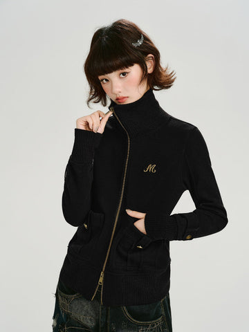 Model wearing a black knit jacket with a full zip closure and a gold embroidered logo on the chest.