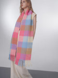 Full body shot of a woman displaying a large, cozy plaid scarf draped around her neck.