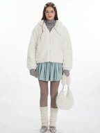 Woman wearing a white fuzzy fleece hooded jacket with bunny ears, a grey turtleneck, a light blue pleated skirt, grey tights, and white leg warmers.