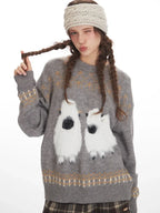 Woman winking while wearing a grey knit sweater with a graphic sheep print and plaid wide leg pants.