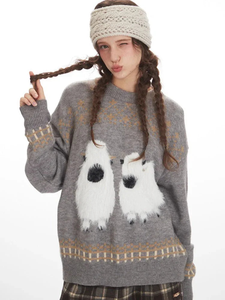 Woman winking while wearing a grey knit sweater with a graphic sheep print and plaid wide leg pants.
