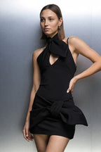 Side view of a black mini dress with an asymmetrical hemline and halter neck