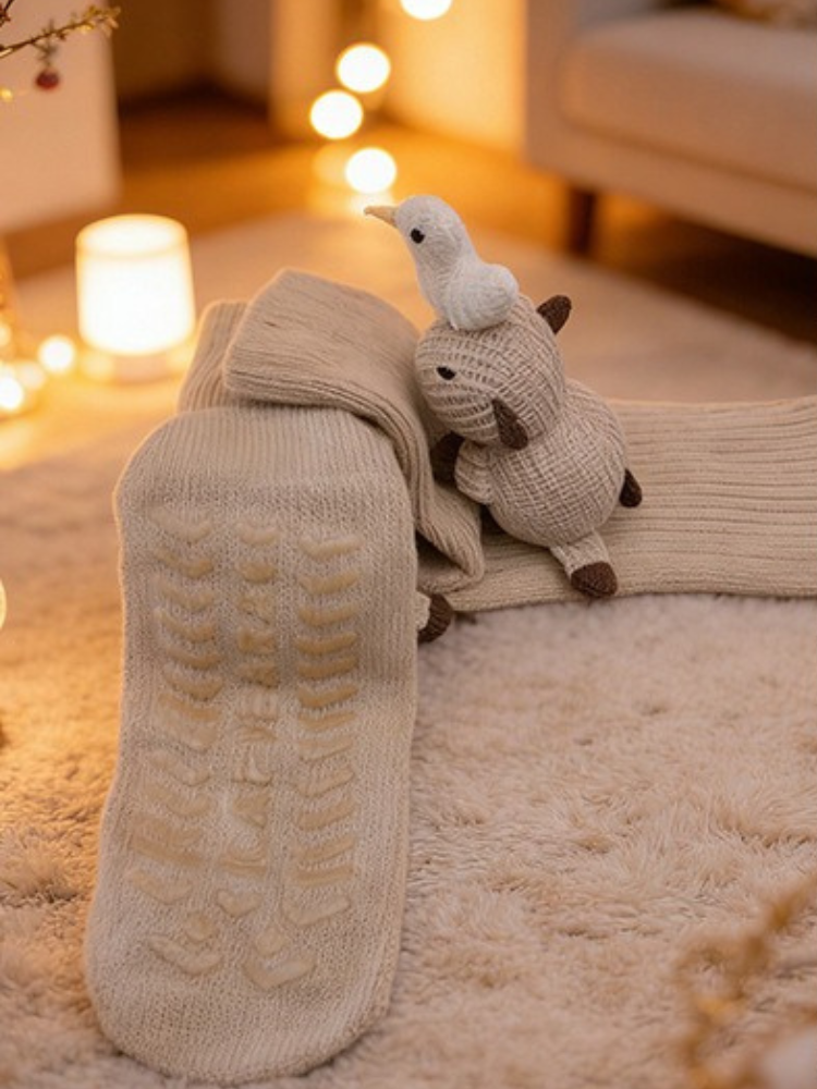 Beige knitted ankle socks with a crochet sheep and duck applique on the side, displayed on a mannequin foot.