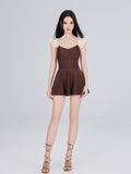 Front view of a woman in a brown one-piece swimsuit with cream ruffle trim on the sleeves and leg openings.