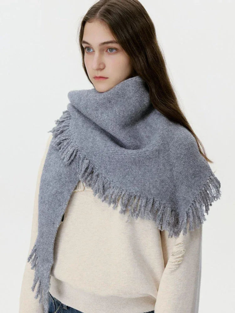 Woman wearing a grey knit scarf with fringe detail over a cream sweater.