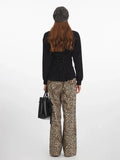 Back view of a model wearing a black V-neck long-sleeve top with a lace-up detail and leopard print wide-leg pants.