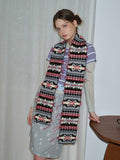 Close-up of a woman wearing a multi-colored knit scarf with geometric designs.
