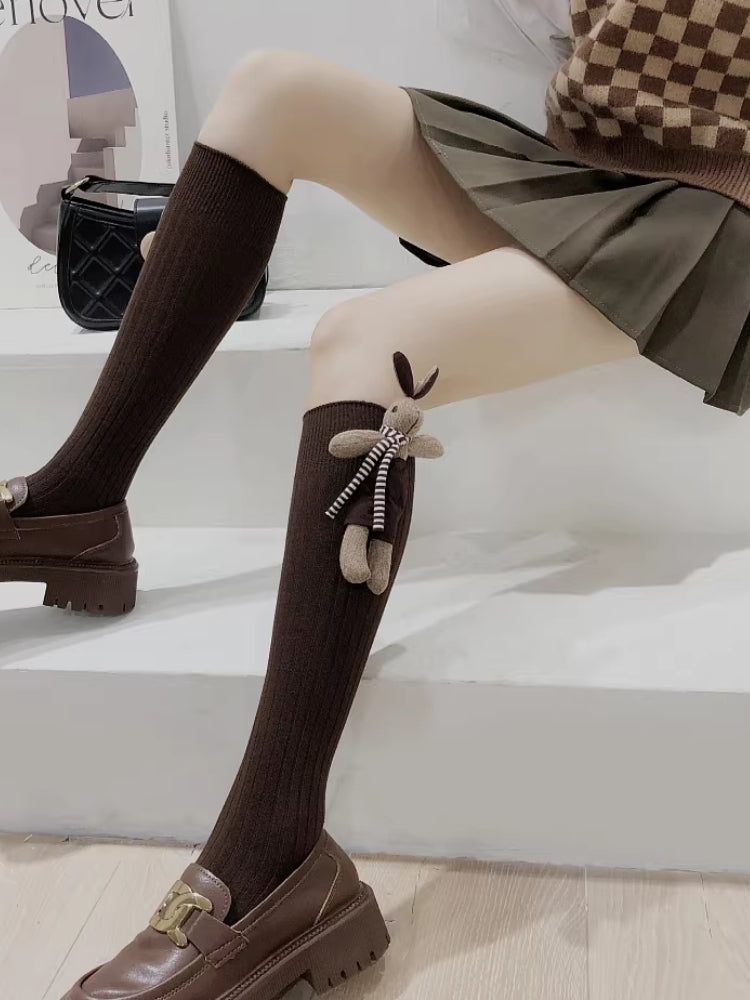 Brown crew socks with a 3D bunny embellishment and striped scarf detail shown with loafers.