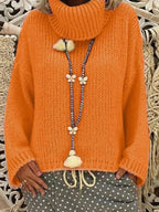 Woman wearing an orange chunky knit turtleneck sweater with a detailed beaded necklace featuring butterfly charms.