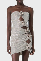 Woman wearing a sparkling silver strapless mini dress with cut-out details and rose embellishments.