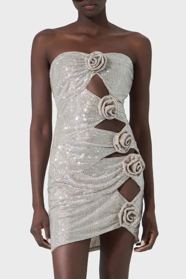 Woman wearing a sparkling silver strapless mini dress with cut-out details and rose embellishments.