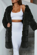 Woman in a grey faux fur coat with a white top and skirt