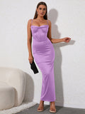 Woman holding a clutch and wearing a lavender satin midi dress with a corset bodice and spaghetti straps.