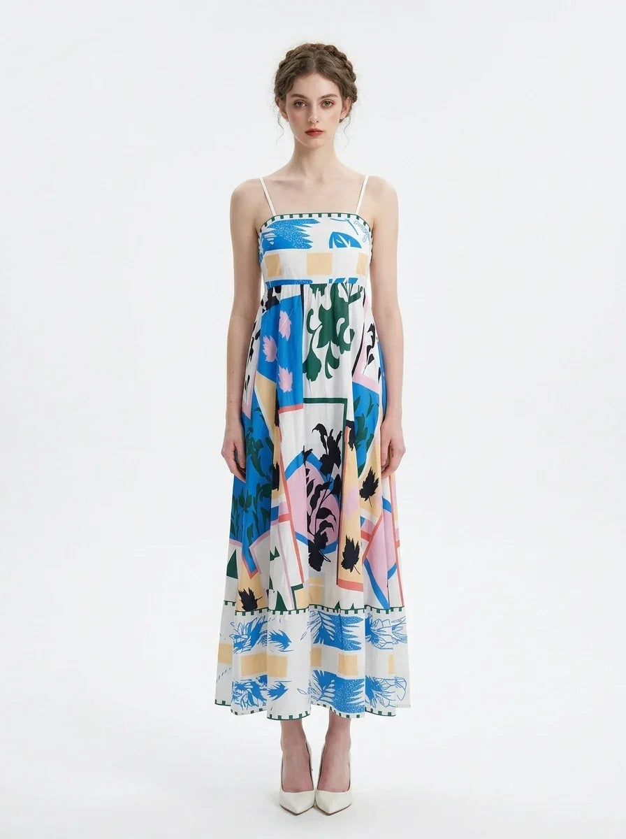 Woman wearing a white midi dress with an abstract botanical print and spaghetti straps, standing against a white background.