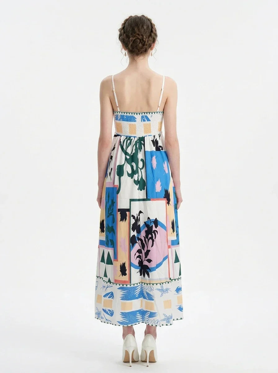 Woman wearing a white midi dress with an abstract botanical print and spaghetti straps, standing against a white background.