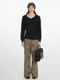 Model wearing a black V-neck long-sleeve top and leopard print wide-leg pants, holding a black handbag.