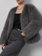 Woman wearing a grey faux fur cropped jacket with long sleeves.