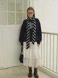Side view of a model in a navy graphic print sweatshirt and white tiered lace skirt, showcasing the relaxed fit and sleeve detail.