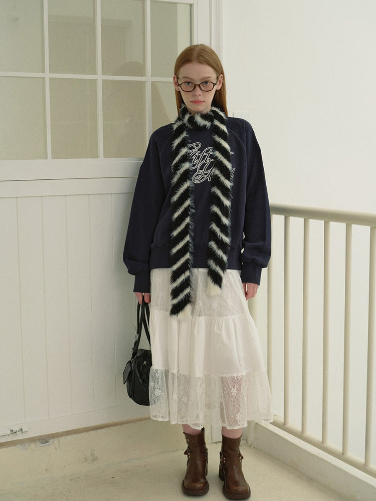 Side view of a model in a navy graphic print sweatshirt and white tiered lace skirt, showcasing the relaxed fit and sleeve detail.