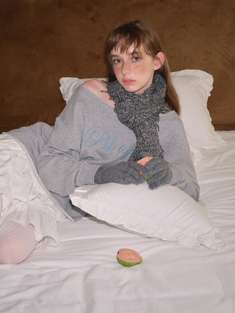 Young woman in grey loungewear and white ruffled skirt, holding a camera.