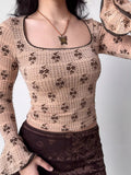 Woman in a beige floral print top with square neckline and bell sleeves.
