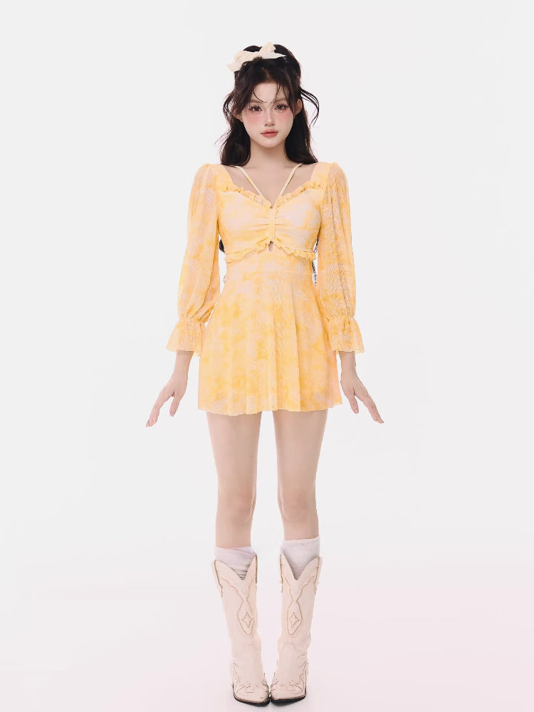 Woman wearing a yellow tie-dye mini dress with long puff sleeves and ruffled trim.