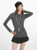 Model posing with heathered gray long sleeve top and ruched design