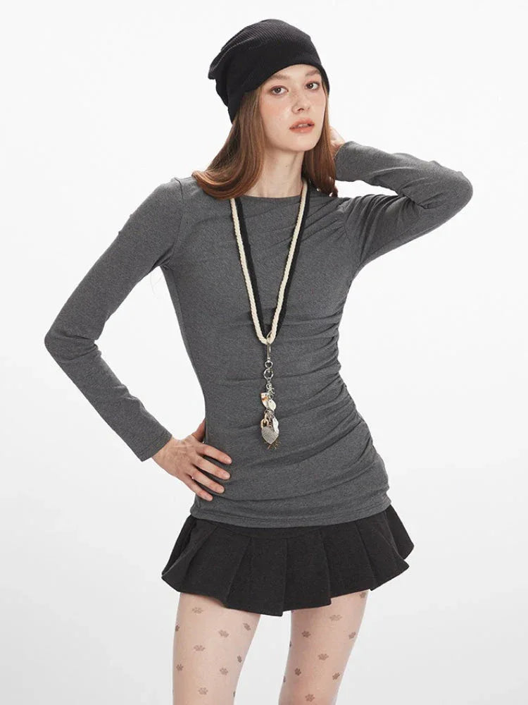 Model posing with heathered gray long sleeve top and ruched design